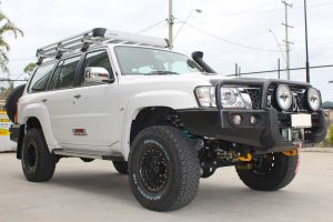 Front right view of a white GU Nissan Patrol Wagon after being fitted with a full 2 Inch Superflex Lift Kit featuring Airbag Man airbags