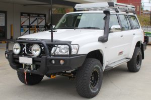 Front left view of a white GU Nissan Patrol Wagon after being fitted with a full 2 Inch Superflex Lift Kit featuring Airbag Man airbags