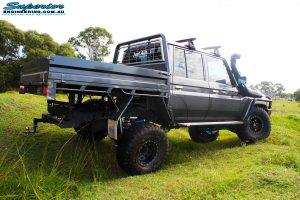 Rear right side view whilst flexing of a Grey Toyota 79 Series Landcruiser Dual Cab after fitment of a Superior 4" Inch Rear Coil Conversion Kit with Hyperflex Radius Arms, Remote Reservoir Shocks and a Airbag Man 4" Inch Coil Helper Air Kit.