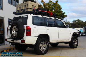 Rear right view of a Nissan GU Patrol Wagon in White fitted with a Airbag Man Coil Air Kit 3" Inch Lift Kit & Superior Tie Rod Comp Spec 4340m Solid Bar whilst on the hoist at Superior