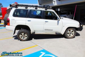 Right side view of a flexed White Nissan GU Patrol Wagon before fitment of a Superior Nitro Gas 2" Inch Lift Kit, Coil Tower Brace Kit, Superior Hybrid Superflex Radius Arms, Airbag Man Coil Air Kit and Superior Adjustable Hollow Bar Drag Link