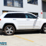 Right side view of a White Jeep WK2 Grand Cherokee being fitted with an Airbag Man Coil Helper Air Kit Standard Height