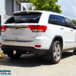 Rear right view of a White Jeep WK2 Grand Cherokee being fitted with an Airbag Man Coil Helper Air Kit Standard Height