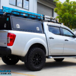 Rear right view of a Grey Nissan NP300 Navara Ute after fitment of a Superior Nitro Gas 4" Inch Lift Kit + Airbag Man 2" Coil Air Kit Helper, Ironman 4x4 Flomax Air Compressor and Nitto Trail Grappler Tyres with King Gator Wheels