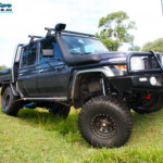 Front right side view whilst flexing of a Grey Toyota 79 Series Landcruiser Dual Cab after fitment of a Superior 4" Inch Rear Coil Conversion Kit with Hyperflex Radius Arms, Remote Reservoir Shocks and a Airbag Man 4" Inch Coil Helper Air Kit.