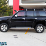 Left side view of a Black Nissan GU Patrol Wagon after being fitted with a Superior 2" Inch Nitro Gas Lift Kit, Airbag Man 2" Inch Coil Air Helper Kit, Safari Snorkel, Brown Davis Long Range Fuel Tank, Superior Coil Tower Brace Kit & Superior Upper Control Arms