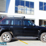Right side view of a Black Nissan GU Patrol Wagon being fitted with a Superior 2" Inch Nitro Gas Lift Kit, Airbag Man 2" Inch Coil Air Helper Kit, Safari Snorkel, Brown Davis Long Range Fuel Tank, Superior Coil Tower Brace Kit & Superior Upper Control Arms