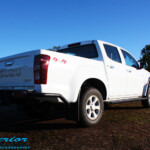 Rear right view of a White Isuzu D-Max Dual Cab being fitted with a Superior Remote Reservoir 2" Inch Lift Kit, Airbag Man Leaf Air Kit, Ironman 4x4 Bullbar + Side Steps, VRS Winch, Safari Snorkel + King Wheels & Nitto Tyres